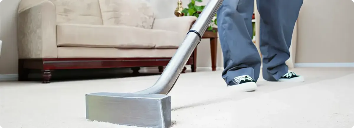 Carpet cleaning technician using a hot-water extraction wand on a light-colored carpet in a living room, Overland Park, KS.